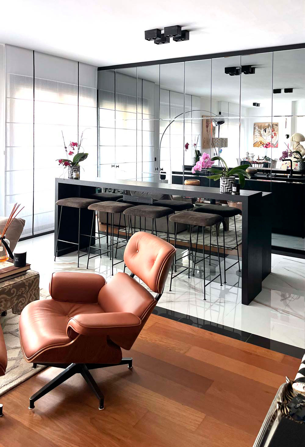 Vivienda con panel de espejo. Suelo de madera y pared negra contrastando con ventanal opuesto.