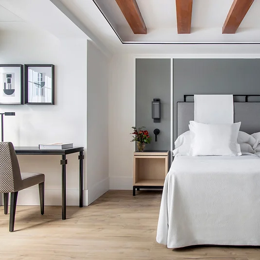 Habitación de hotel. Paredes blancas, suelo y vigas de madera rústica.