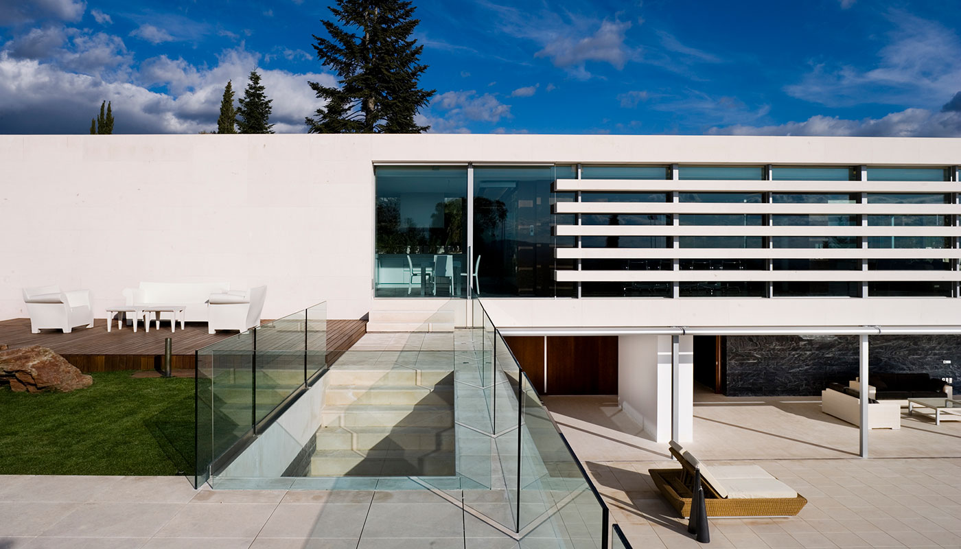 Exterior vivienda unifamiliar. Piedra caliza y cristal. Vista terraza superior.