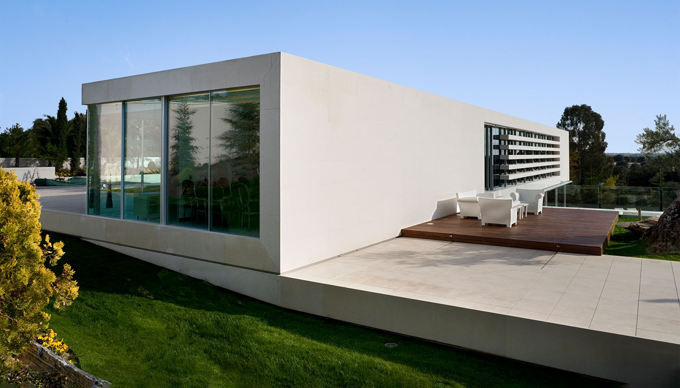 Exterior vivienda unifamiliar. Piedra caliza y cristal. Vista trasera