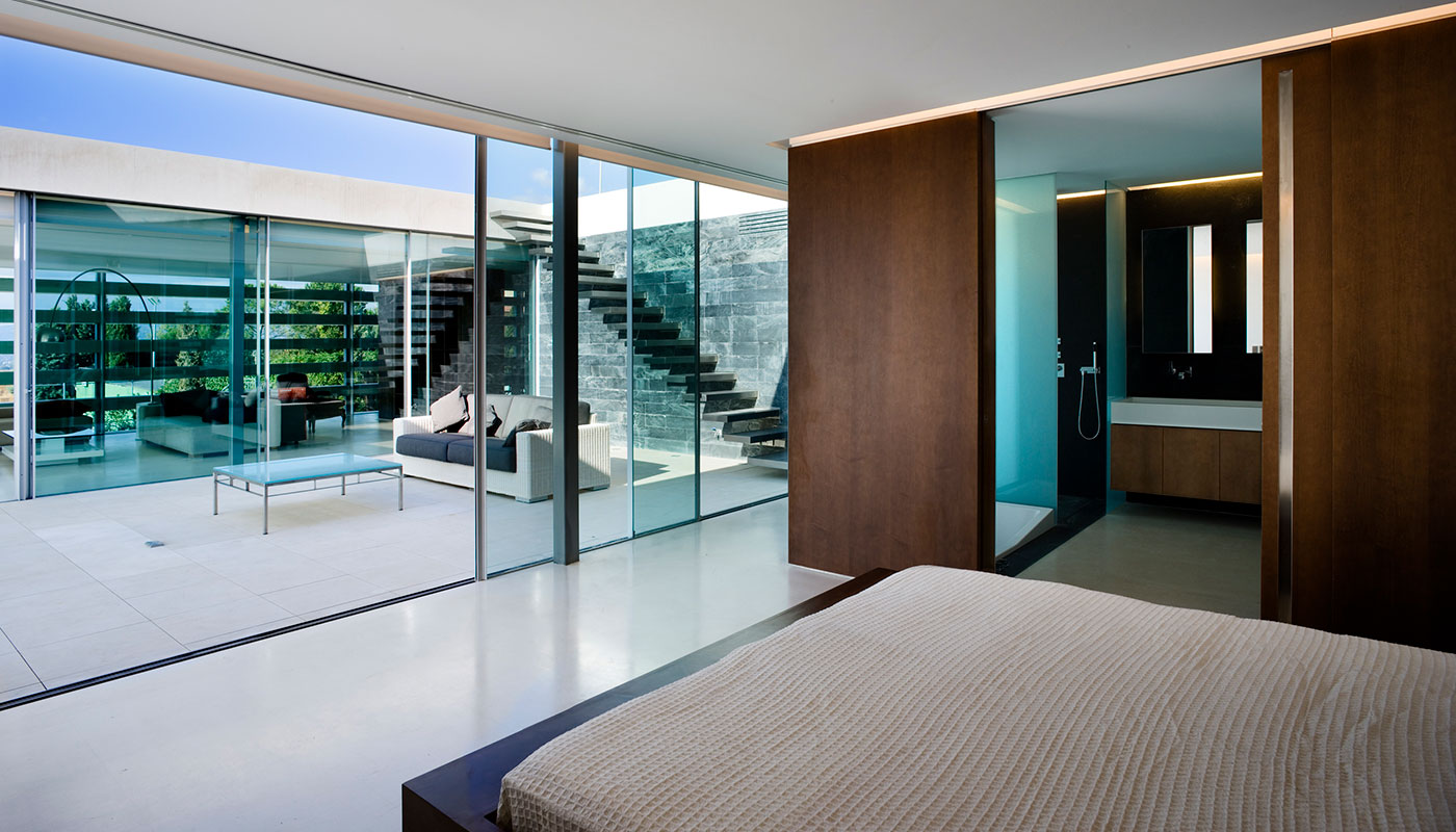 Vista Interior dormitorio. Piedra caliza, madera y cristal.