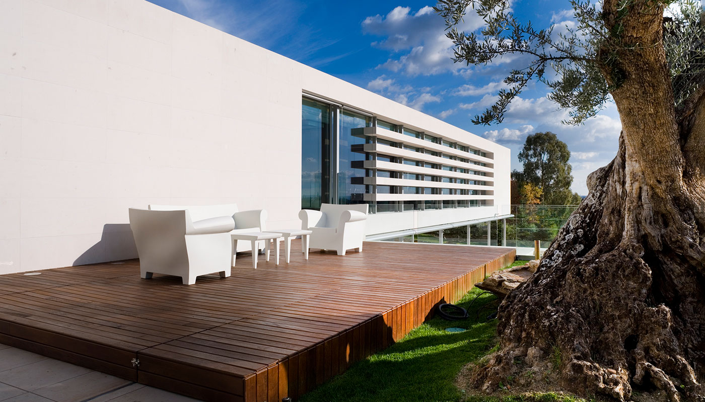 Exterior vivienda unifamiliar. Piedra caliza y cristal. Vista terraza superior trasera.