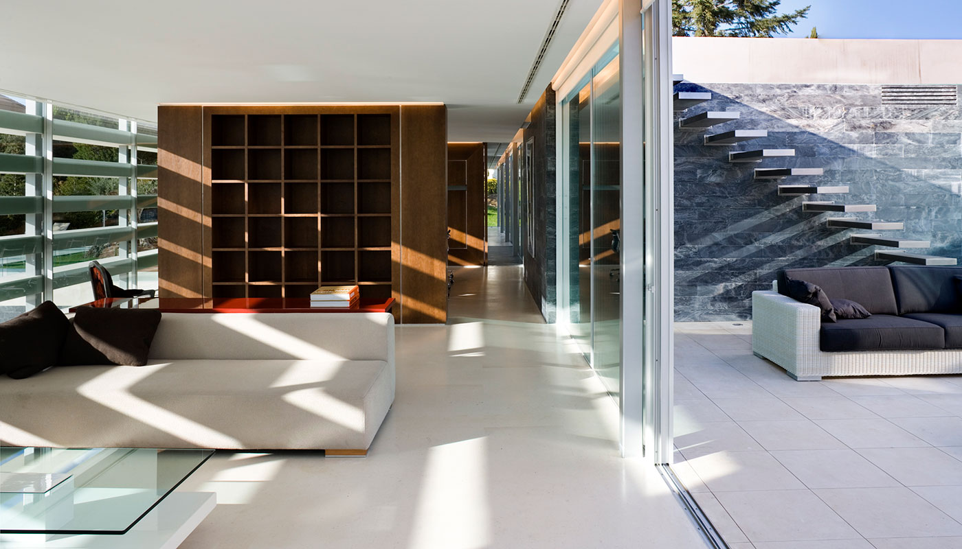 Vista Interior salón y exterior patio. Piedra caliza, madera y cristal.