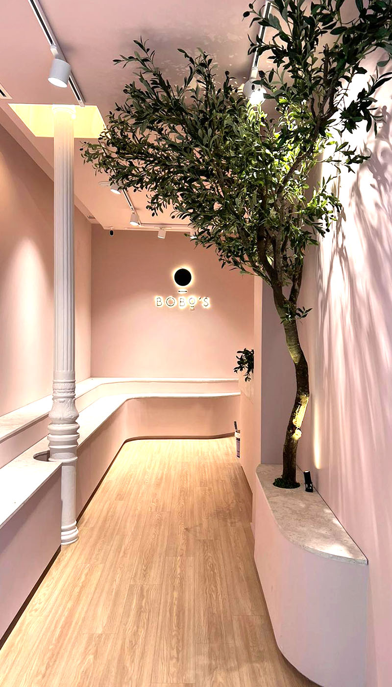 Interior tienda zapatería. Paredes rosas y suelo de madera.