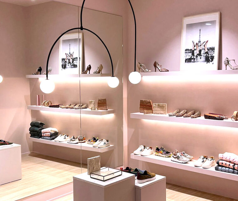 Interior tienda zapatería. Paredes rosas y suelo de madera.