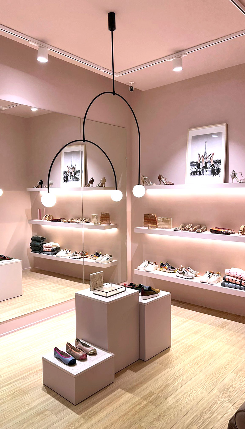 Interior tienda zapatería. Paredes rosas y suelo de madera.