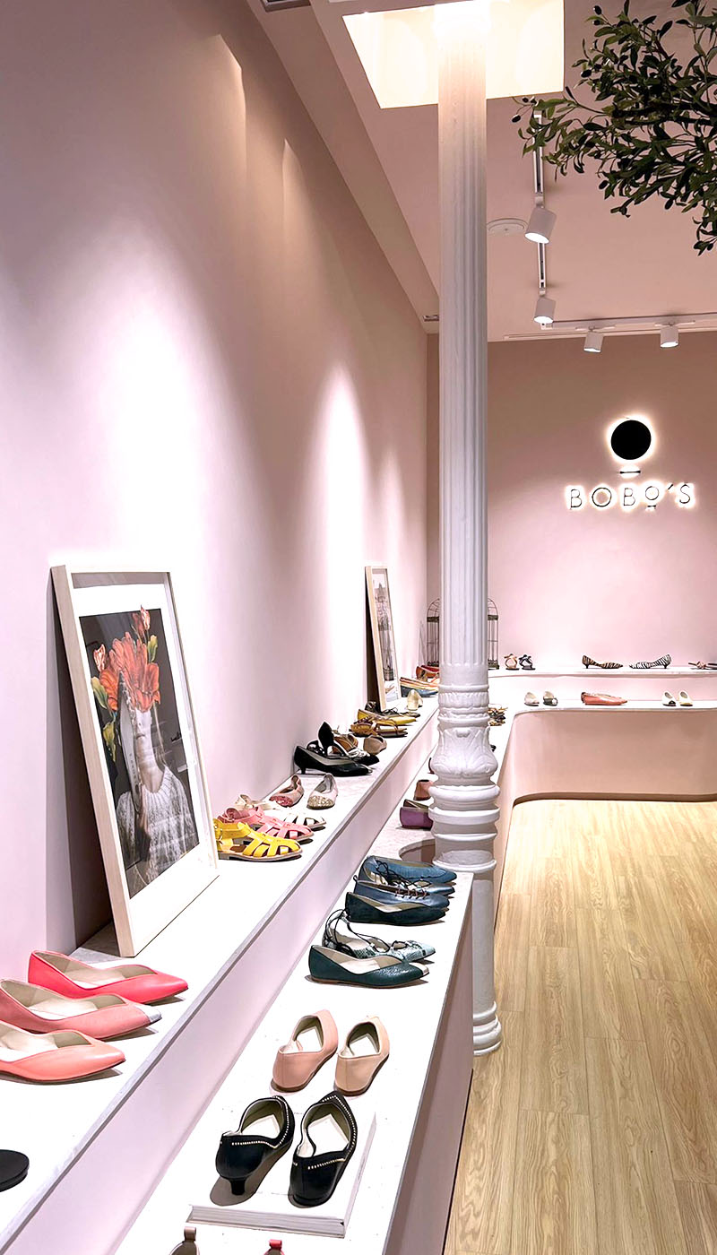 Interior tienda zapatería. Paredes rosas y suelo de madera.