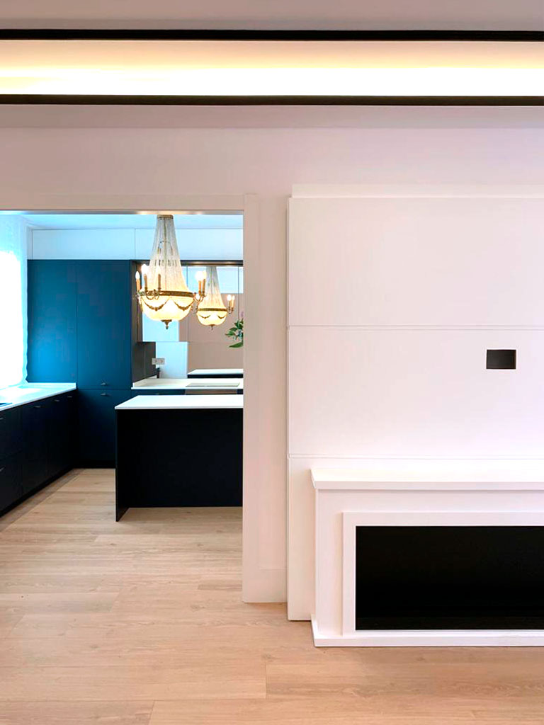 Interior vivienda salón madera y blanco con pared azul de fondo.