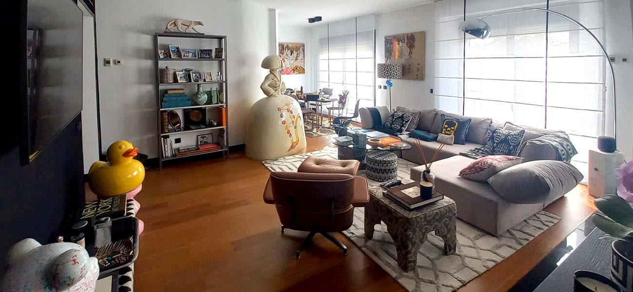 Interior vivienda con un gran panel trasero de espejo. Suelo de madera y pared negra contrastando con el gran ventanal opuesto.