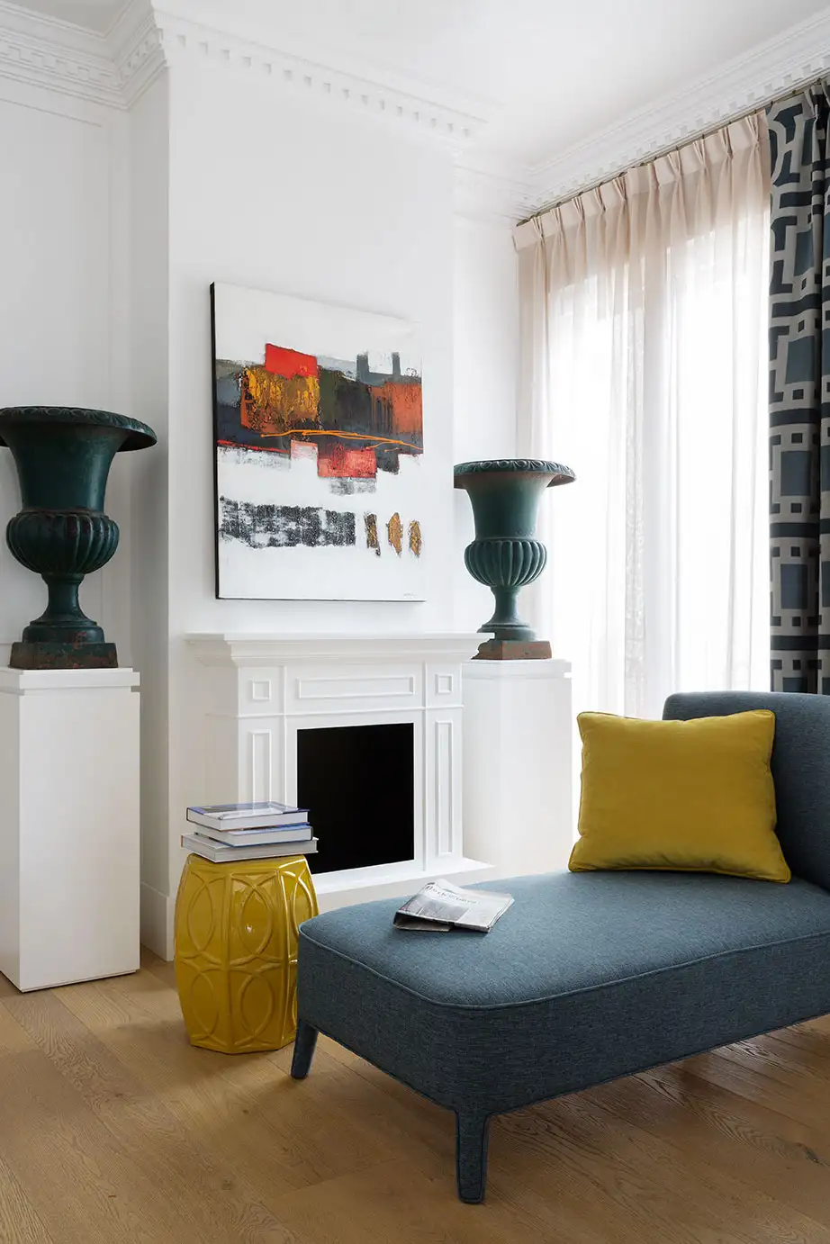 Vivienda con paredes blancas y suelo de madera. Dos jarrones y un sofá azul.