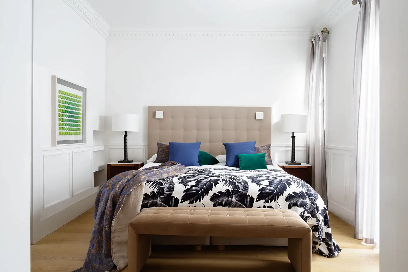 Vista interior de dormitorio de una vivienda con paredes blancas y suelo de madera. Decoración minimalista, colores crema.