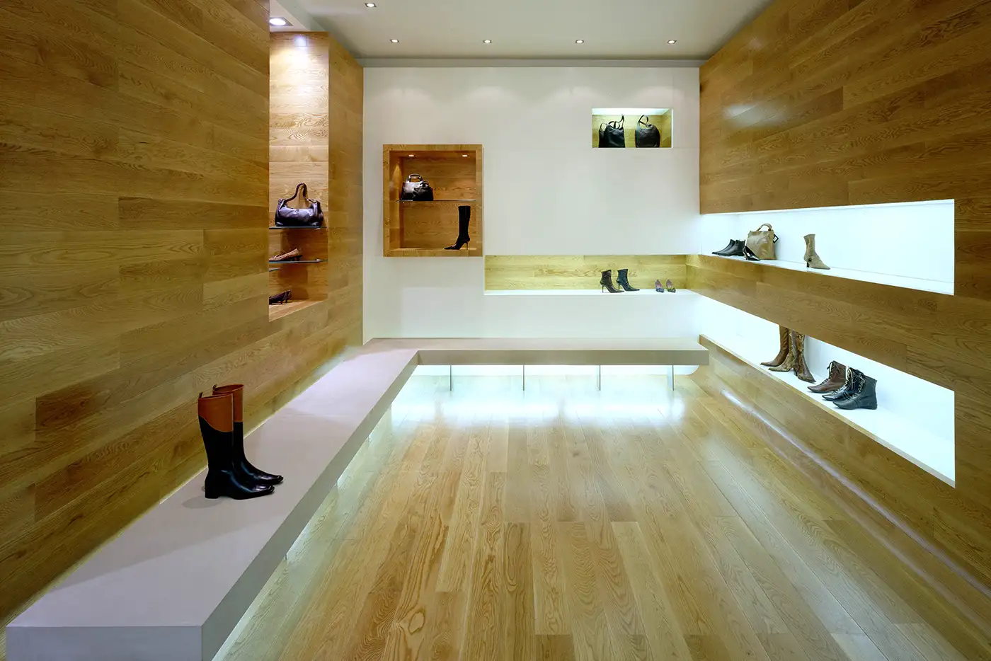 Vista del panel frontal. Interior zapatería, decoración minimalista, suelo de madera. Tonos crema suave.