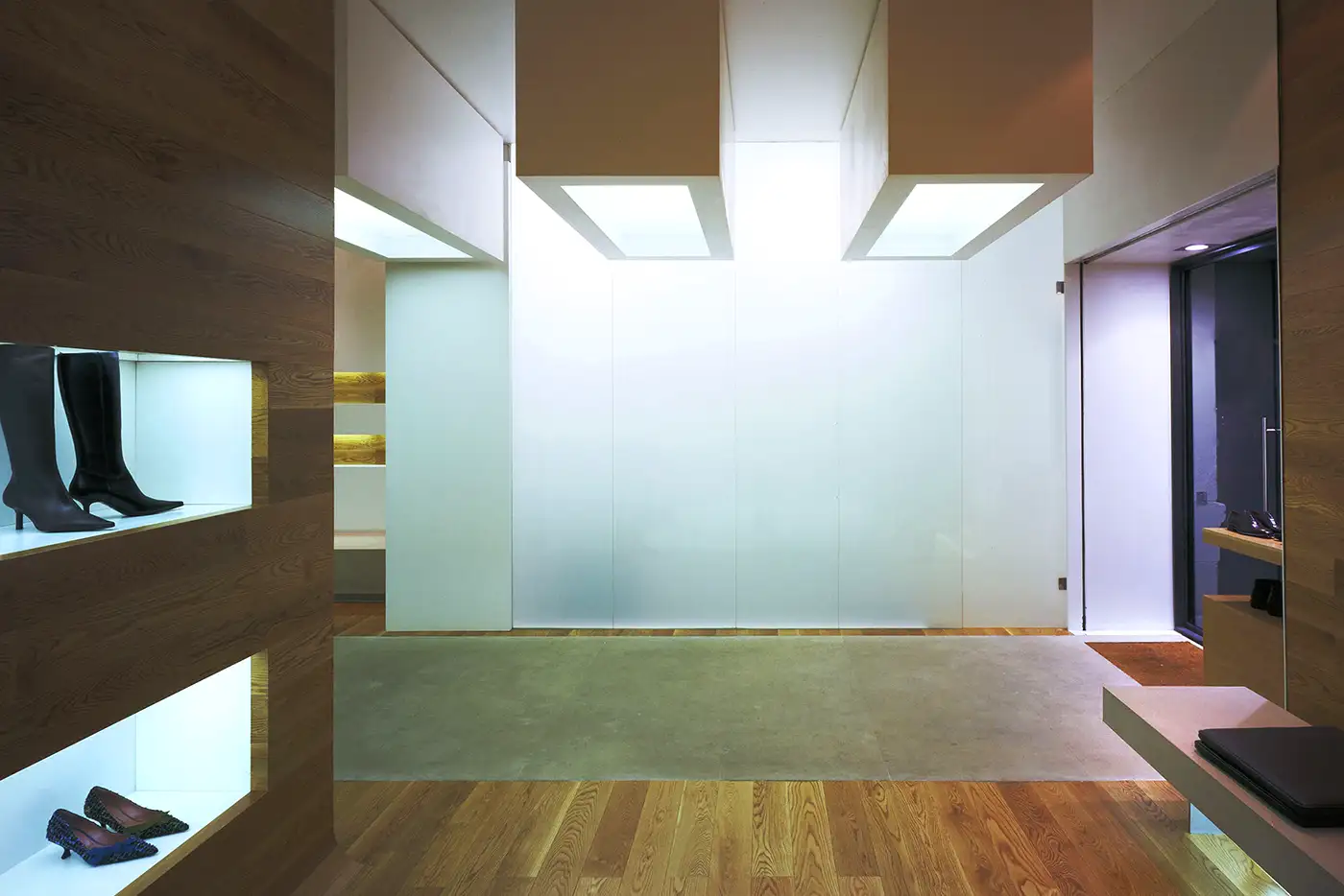 Vista del panel frontal. Interior zapatería, decoración minimalista, suelo de madera. Tonos crema suave.