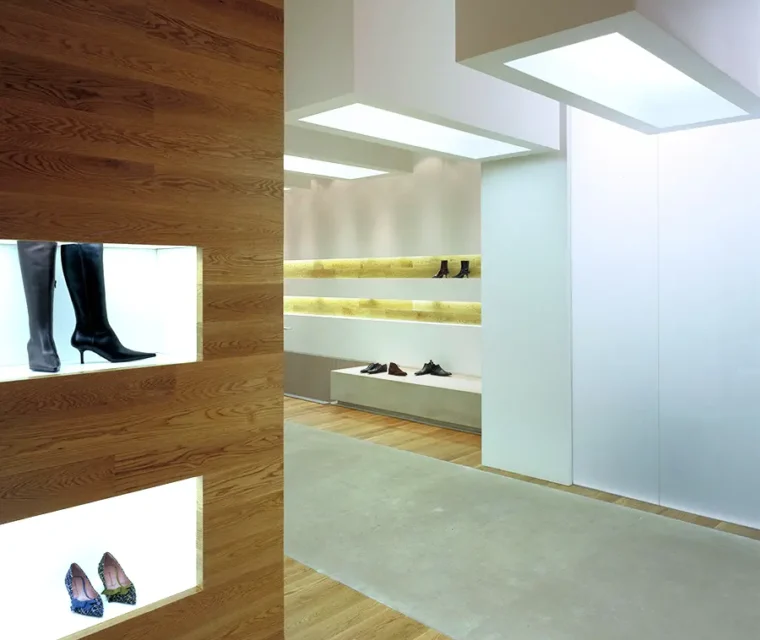 Interior zapatería, decoración minimalista, suelo de madera. Tonos crema suave.