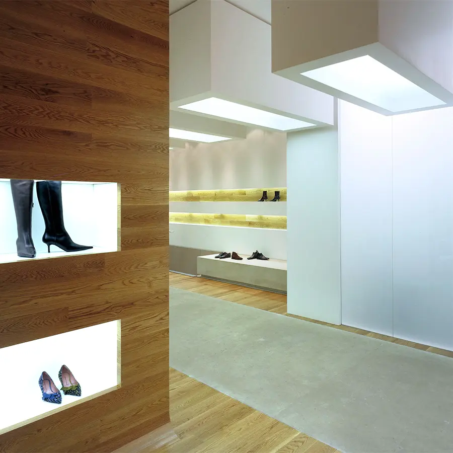 Interior zapatería, decoración minimalista, suelo de madera. Tonos crema suave.