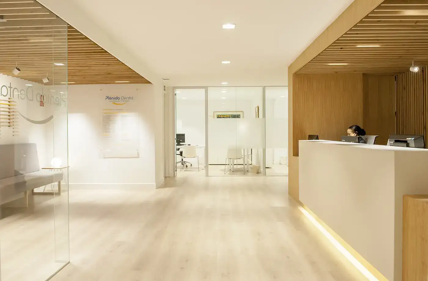 Interior clínica dental. Iluminación cálida, tonos crema y madera.