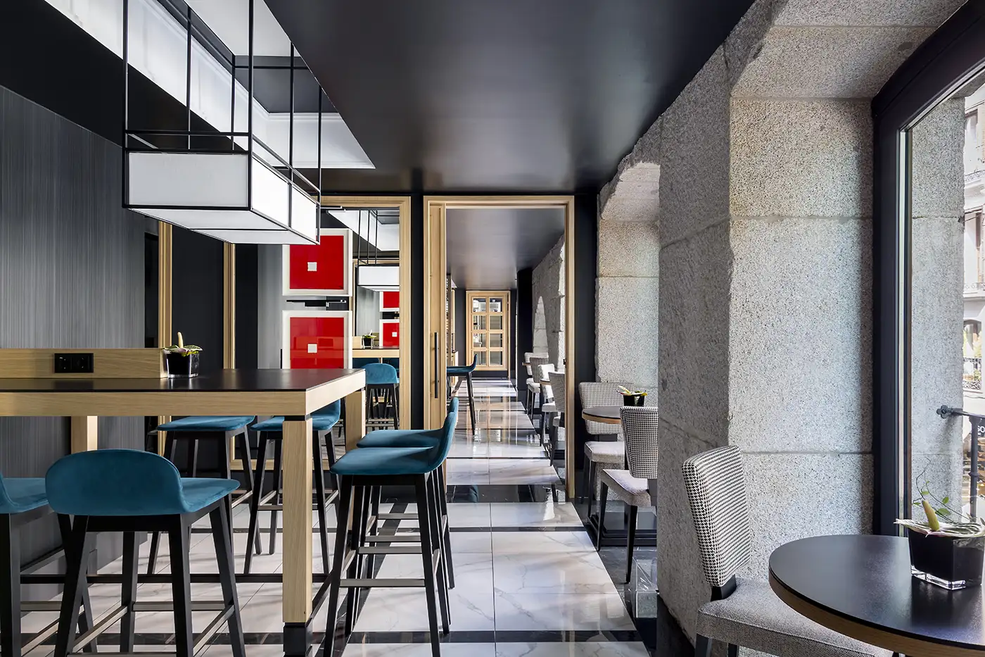 Interior restaurante, techos altos, abundante iluminación. Detalles en rojo y tapicerías en tonos azules.