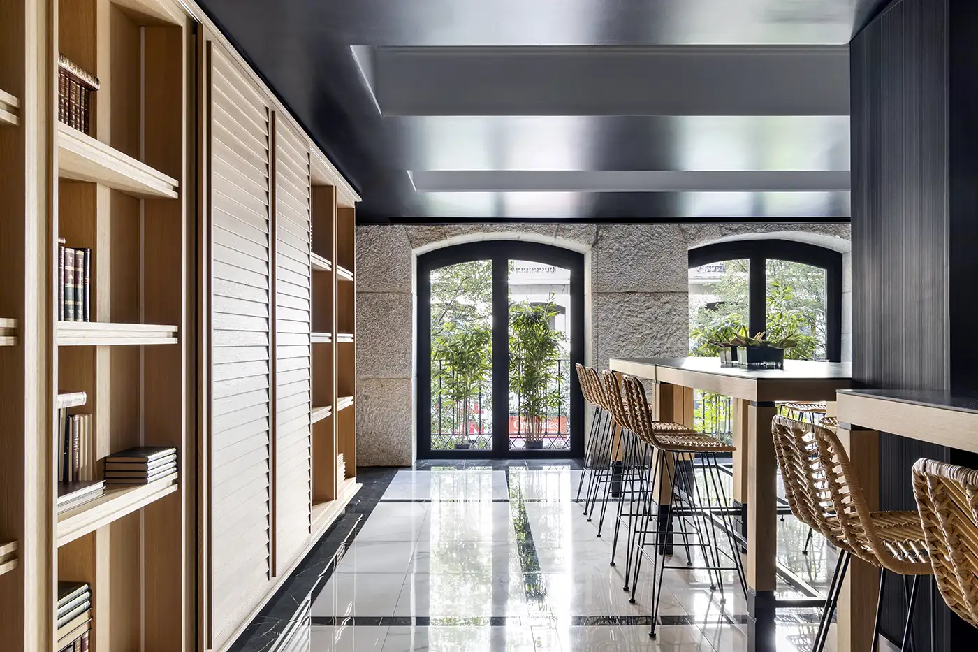 Interior restaurante. Vista frontal de muro exterior de piedra. Techos altos, abundante iluminación. Detalles en rojo y tapicerías en tonos azules.