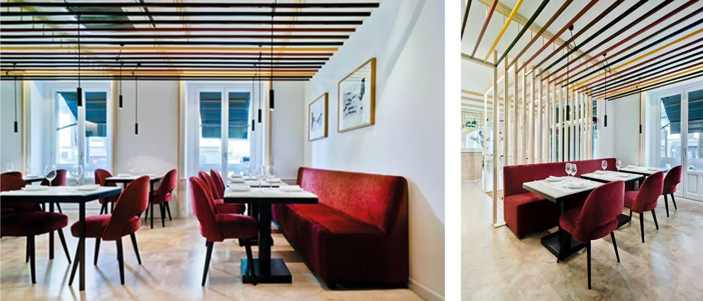 Planta superior de un luminoso restaurante. Zona salón. Decoración en tonos blancos y madera de color claro rematado con tapicería de color rojo anaranjado.