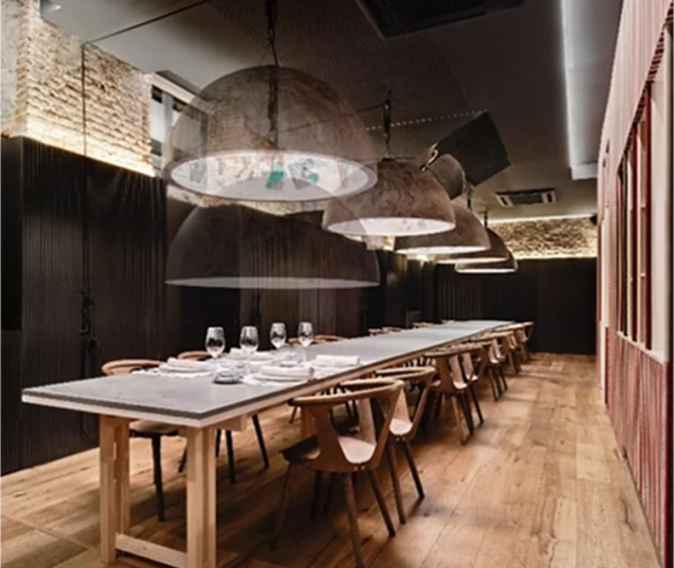 Mesa larga en planta sótano de restaurante. Suelo de madera y paredes de ladrillo.