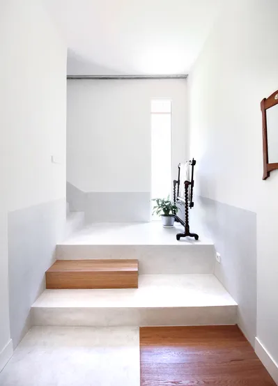 Vista de escalera de obra en el interior de vivienda. Tonos claros con detalles en madera.