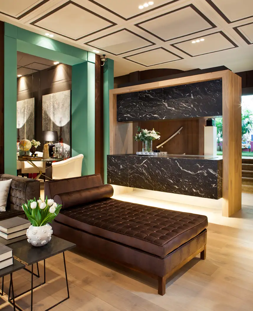 Interior con diván. Suelo de madera y pared verde. Mueble acabado en madera y marmol.