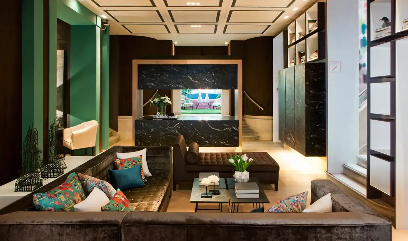 Vista interior de una estancia con suelo de madera y paramentos verticales acabados en color verde, madera y marmol negro.