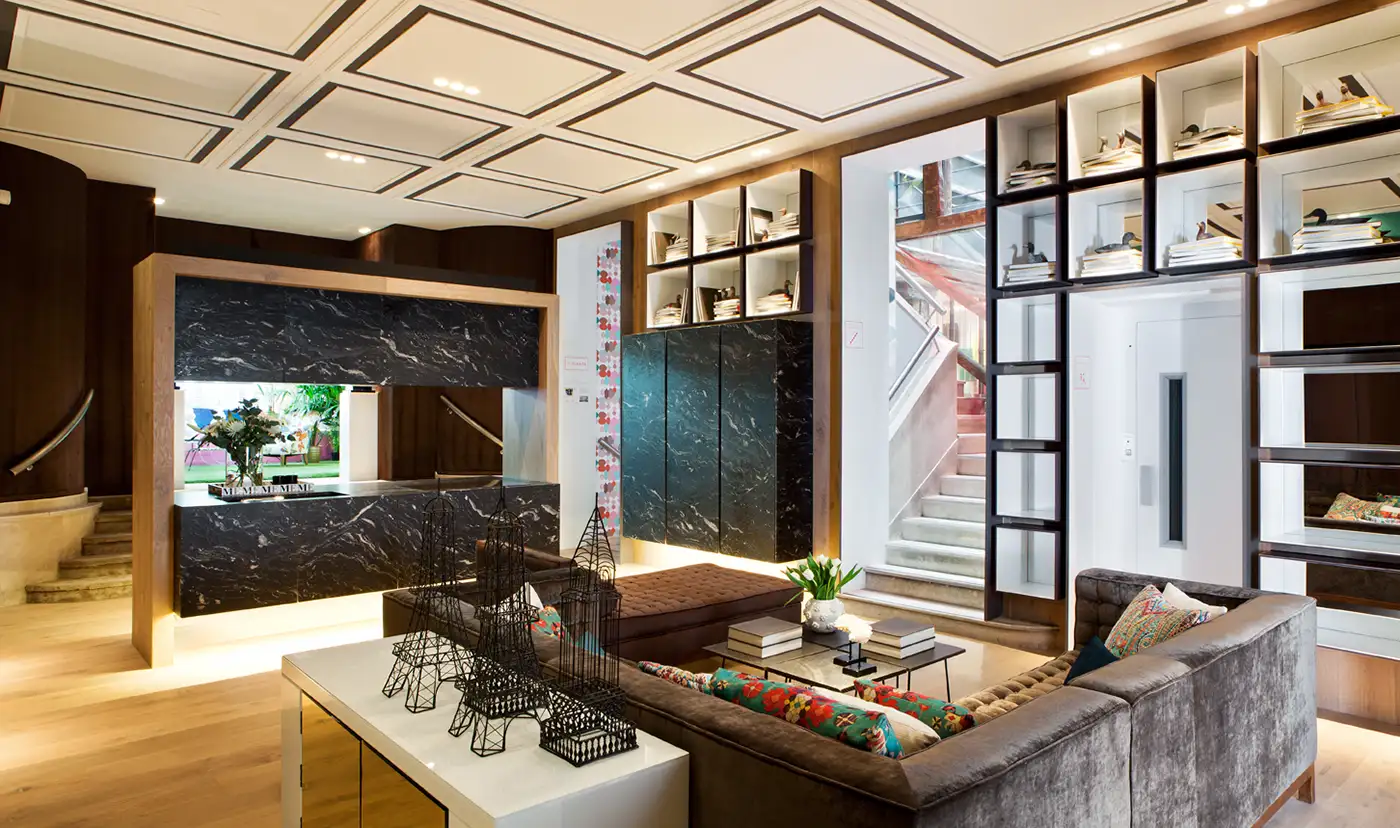 Vista interior de una estancia con suelo de madera y paramentos verticales acabados en color verde, madera y marmol negro.