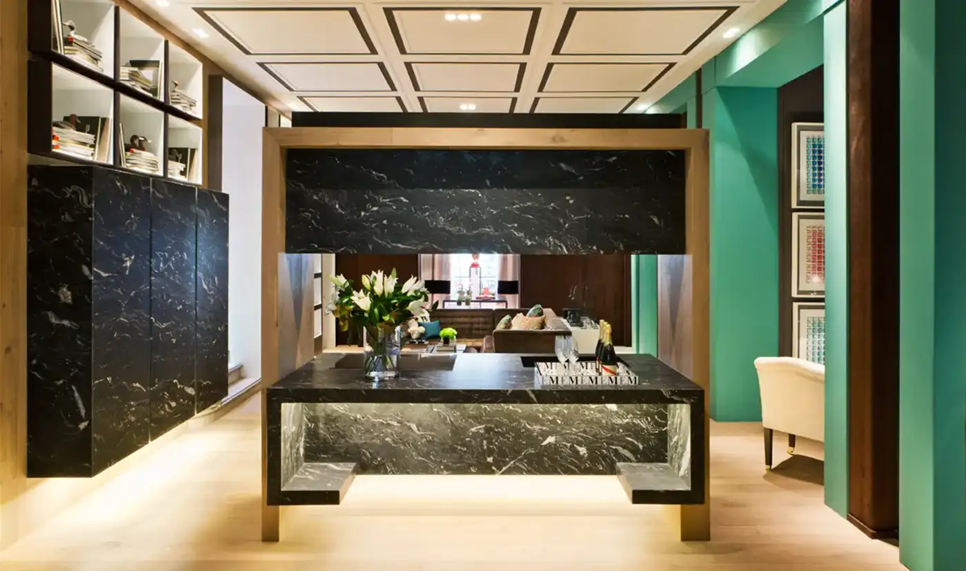 Vista interior de una estancia con suelo de madera y paramentos verticales acabados en color verde, madera y marmol negro.