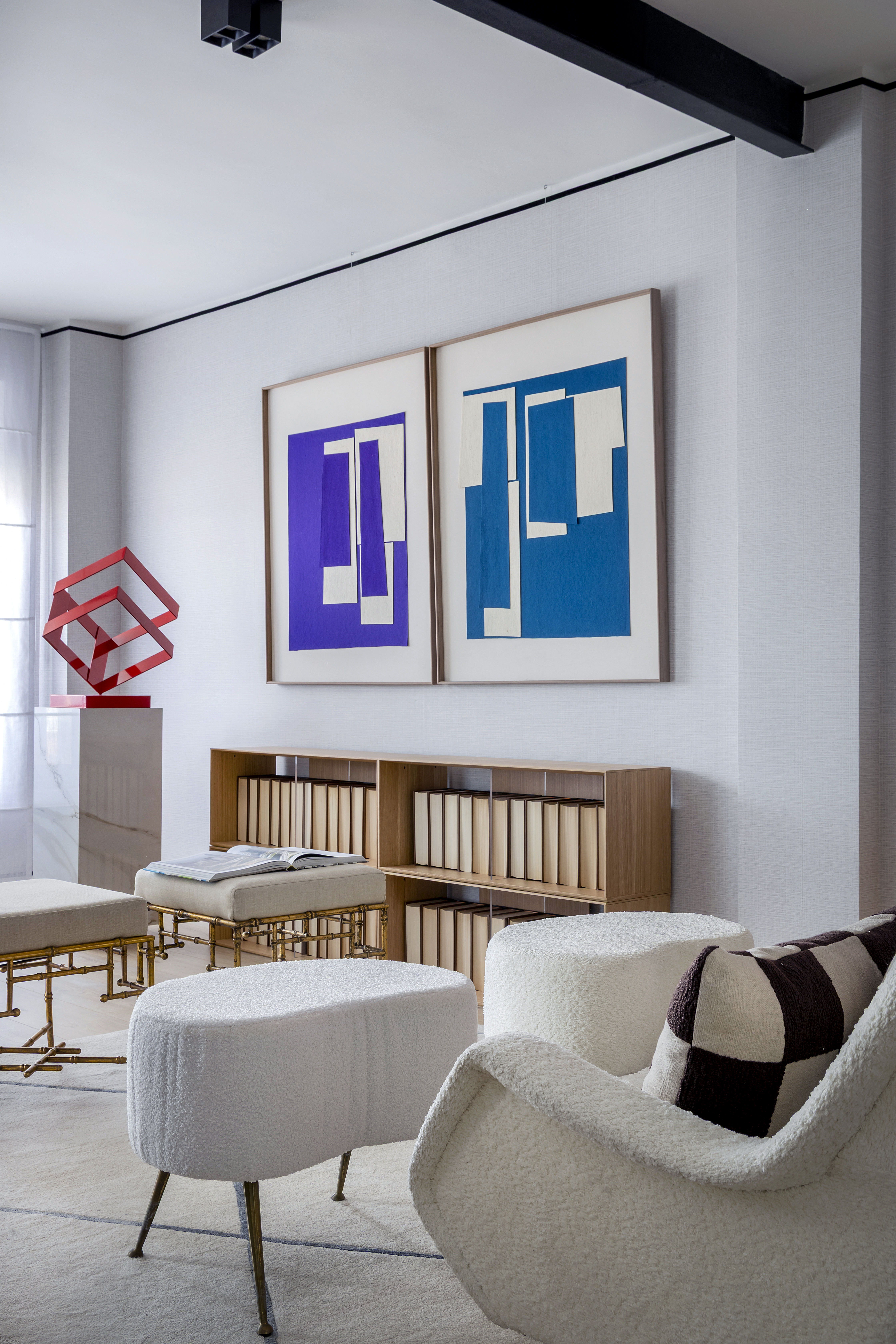 Detalle del salón con obras de arte en la pared, mobiliario auxiliar, taburetes tapizados y elementos decorativos.