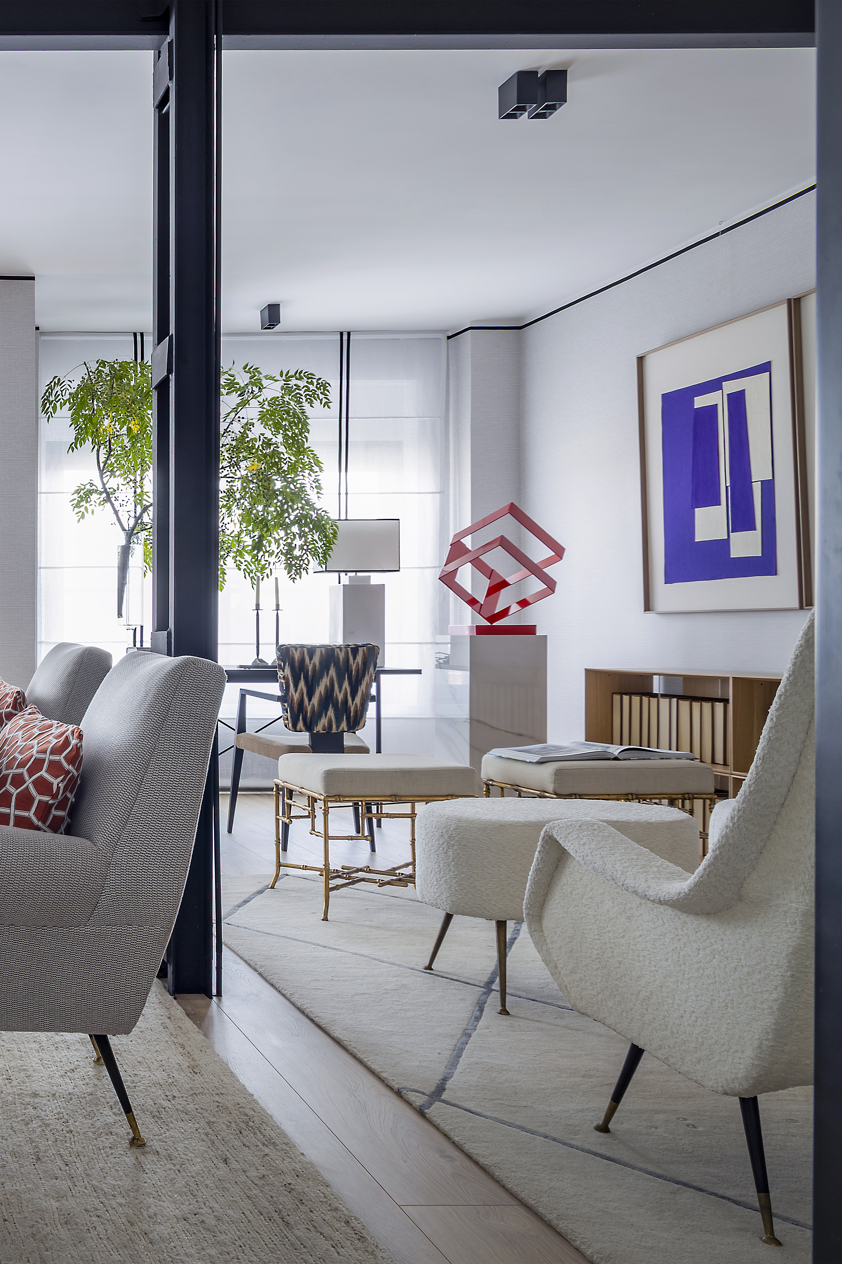 Vista amplia del salón con zona de estar, área de trabajo al fondo, mobiliario contemporáneo y elementos decorativos.