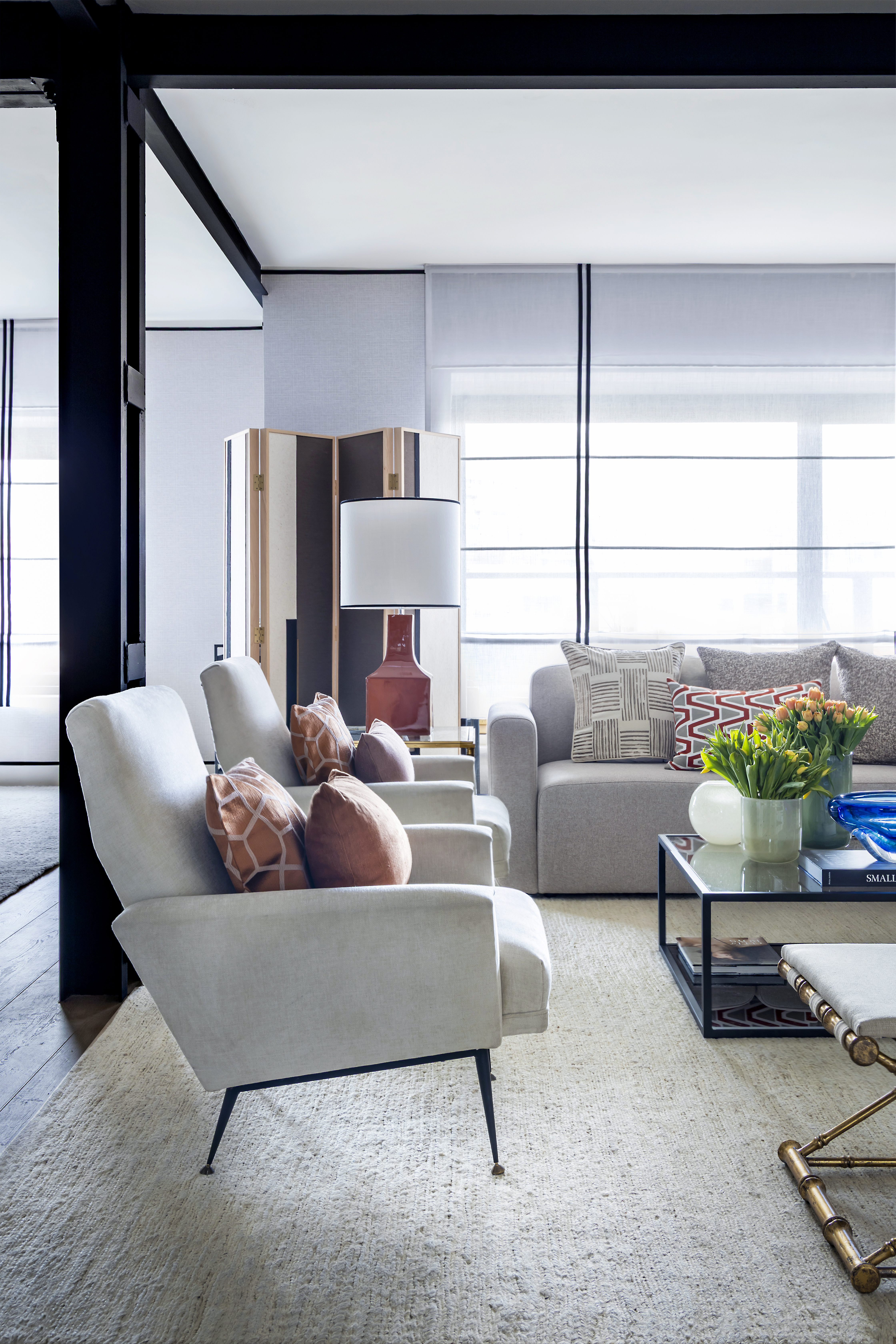 Zona de estar del salón con butacas tapizadas, sofá, mesa de centro con elementos decorativos y entrada de luz natural.