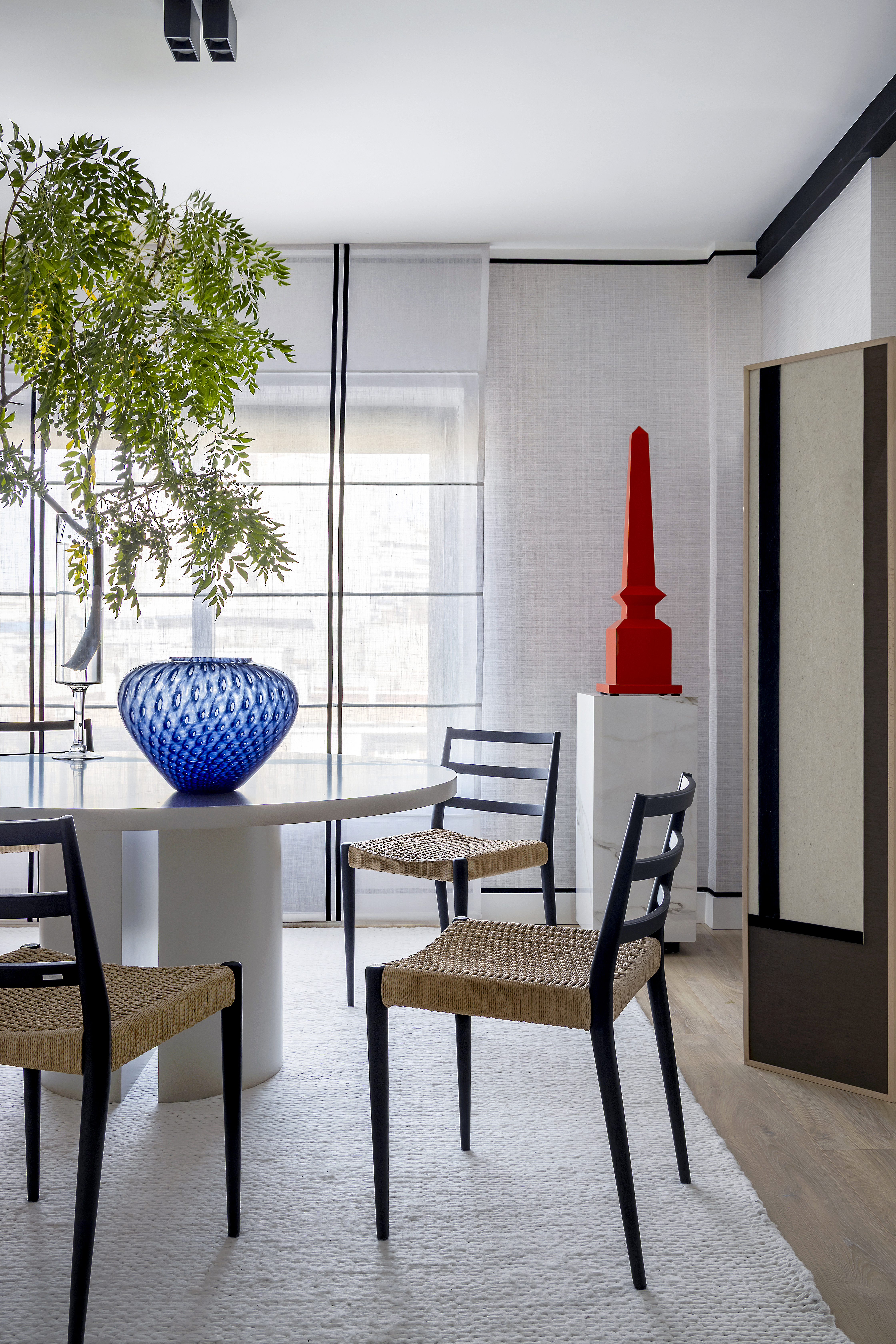 Zona de comedor con mesa redonda, sillas, elementos decorativos y entrada de luz natural.