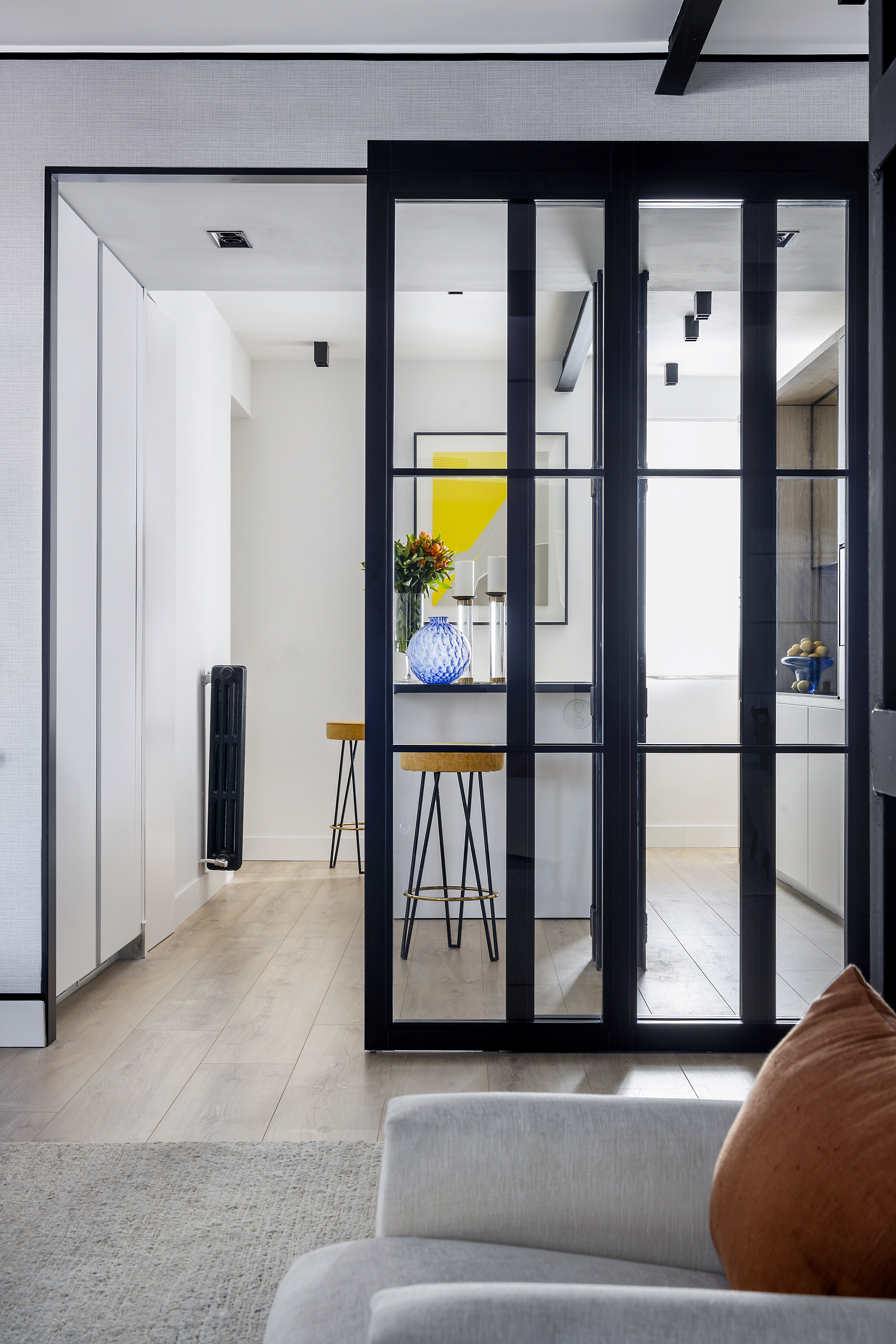 Acceso a la cocina a través de puerta corredera acristalada, con barra de cocina y taburetes visibles.